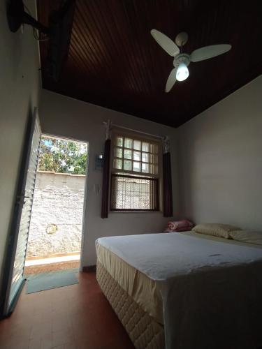 a bedroom with a bed with a ceiling fan and a window at Pousada Recanto da Praia in Bertioga