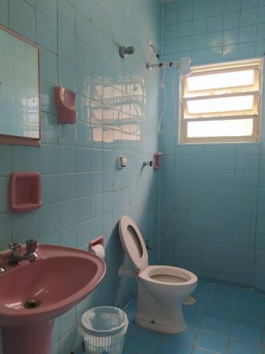 a bathroom with a pink sink and a toilet at Pousada Recanto da Praia in Bertioga