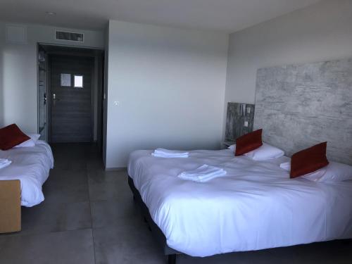 a bedroom with two beds with red pillows on them at Hôtel L'Isula Marina in LʼÎle-Rousse