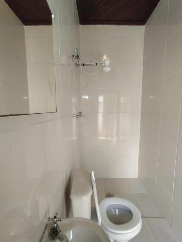 a white bathroom with a toilet and a sink at Pousada Recanto da Praia in Bertioga