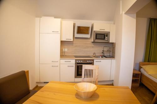 a small kitchen with white cabinets and a wooden table at Gasthof-Pension Riedl in Vöcklamarkt