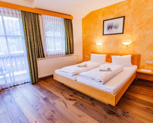 a bedroom with a large bed with white sheets at Gästehaus Hartweger in Haus im Ennstal