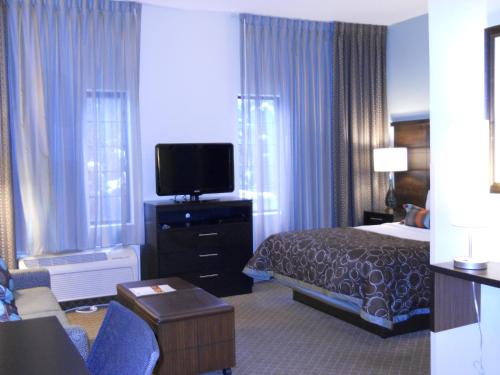a hotel room with a bed and a flat screen tv at Staybridge Suites Columbus-Airport by IHG in Columbus