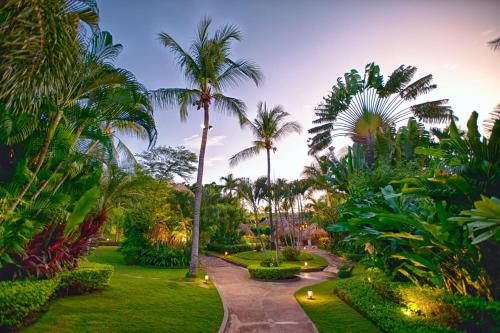 a garden with palm trees and lights at dusk at Jardin del Eden Boutique Hotel in Tamarindo