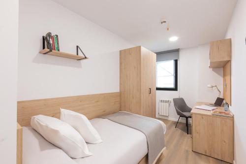 a bedroom with a white bed with a desk and a chair at Micampus Santander in Santander