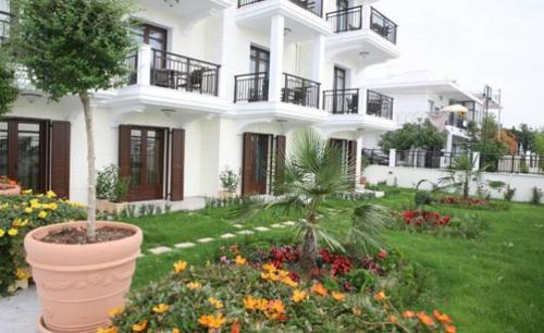 a large white building with flowers in a yard at Makedos Sea View in Nea Vrasna