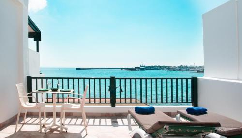balcón con mesa, sillas y vistas al océano en Blancazul Los Clicos en Playa Blanca