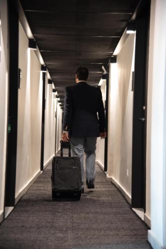 a man walking down a hallway with a suitcase at The 108 Hotel in Islamabad