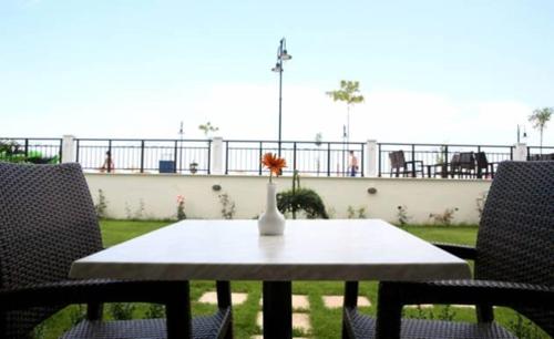 a table with two chairs and a vase with a flower on it at Makedos Sea View in Nea Vrasna