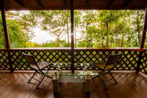 a table and two chairs on a porch with trees at Mirador Valle del General in La Ese
