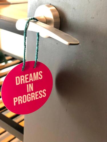 a red sign that says dreams in progress hanging on a door at The 108 Hotel in Islamabad