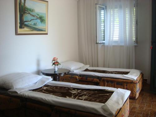 two beds in a room with a table and a window at Apartmani Dragović in Sveti Stefan
