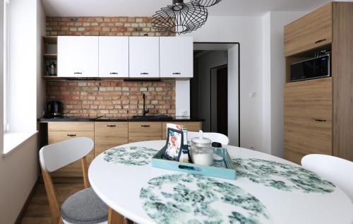 a kitchen with a white table and white chairs at Sea Zone Apartament przy starówce in Wejherowo