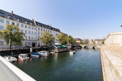 a river with boats in a city with buildings at Hygge Living - Heart of Copenhagen in Copenhagen
