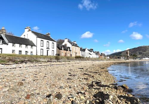 a group of houses on the shore of a beach at Newton Cottage North in Inveraray