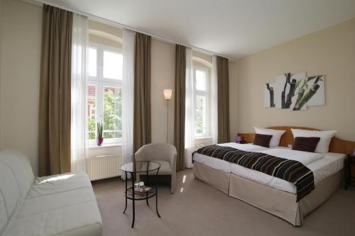 ein Hotelzimmer mit einem Bett und einem Stuhl in der Unterkunft Gut Hotel Stadt Beelitz in Beelitz