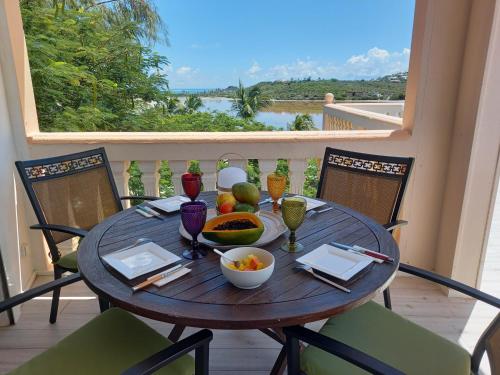 a wooden table with a bowl of fruit on a balcony at Carambola Résidence, Ocean View in Cul de Sac