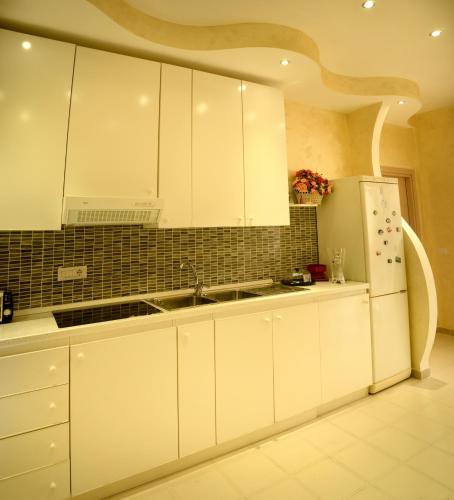a kitchen with white cabinets and a white refrigerator at Apta Mihi B&B in Vico Equense