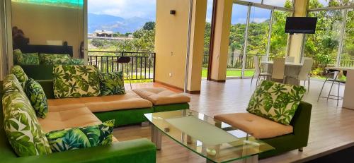 a living room with green furniture and a balcony at Mountain View Anapoima in Anapoima