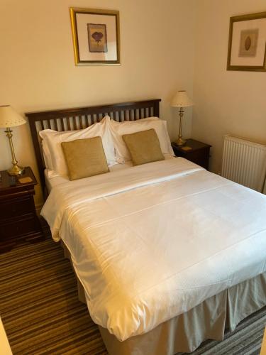 a white bed with a white comforter and pillows at Corncroft Guest House in Witney