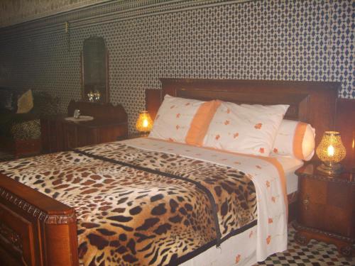 a bedroom with a leopard print bed with two lamps at Riad Les Chrifis Navette Aéroport 24 sur 24 in Fès