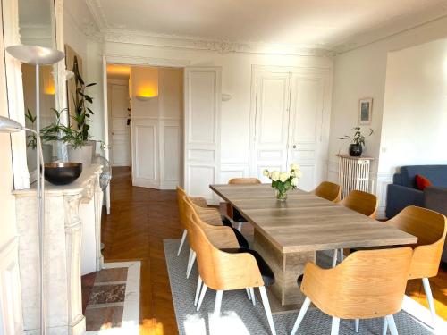une salle à manger avec une table et des chaises en bois dans l'établissement Marvellous Sunbathed 3BR at the heart of Paris, à Paris