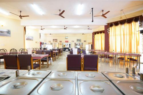 a dining room with tables and chairs and ceiling fans at Hotel TamilNadu - Yercaud in Yercaud
