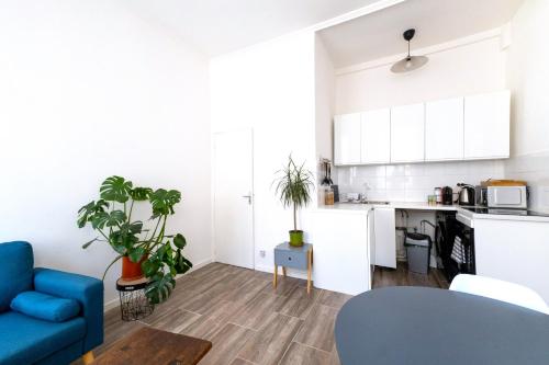 un salon avec un canapé bleu et une cuisine dans l'établissement À 200M de la Gare Matabiau - Appartement tout équipé en Hypercentre -, à Toulouse