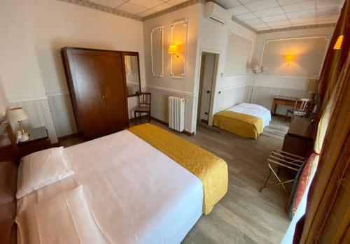 a hotel room with two beds and a desk at Grand Hotel Regina Salsomaggiore in Salsomaggiore Terme