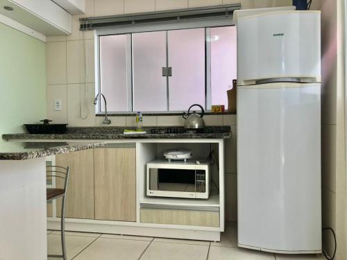 a kitchen with a white refrigerator and a microwave at Kitnet no Centro de Bombinhas in Bombinhas
