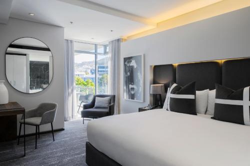 a hotel room with a large bed and a mirror at The Capital 15 on Orange Hotel & Spa in Cape Town