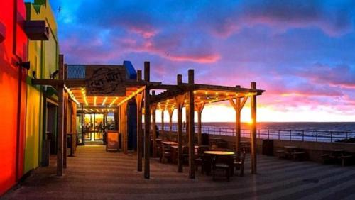 a boardwalk with tables and chairs on the beach at sunset at CJ & Daisies Holiday Home in Prestatyn