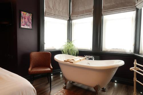 baño con bañera, cama y ventanas en The Craft House en Plymouth