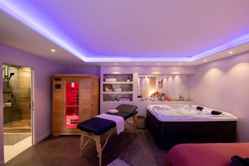 a purple room with a bed and a bath tub at MAISON AVEC SPA PRIVATIF ( JACUZZI ET SAUNA) in Bailleval