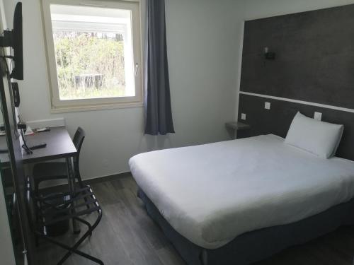 a bedroom with a bed and a desk and a window at Hôtel Arc-En-Ciel - Entièrement Rénové in Mulhouse