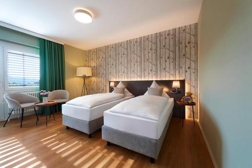 two beds in a hotel room with green curtains at Landgasthof Kranz in Ohlsbach