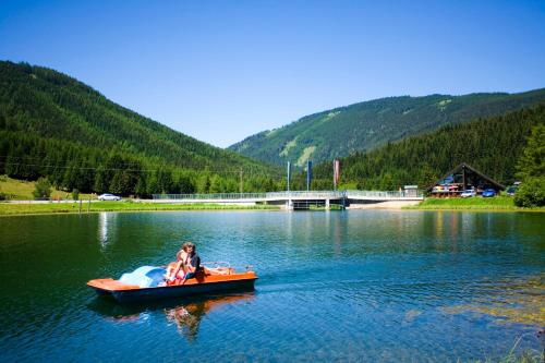 a woman and a child in a boat on a lake at Hotel Teichwirt in Fladnitz an der Teichalm