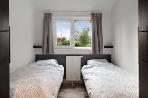 2 bedden in een slaapkamer met een raam bij Luxe chalet in Oosterwolde in FRIESLAND, op rustig park met uitzicht op meer en strandje in Oosterwolde