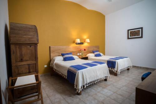 a hotel room with two beds and a table at Parador San Agustin in Oaxaca City
