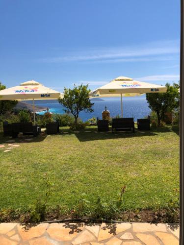 two umbrellas sitting on a lawn near the water at Lumra Rooms in Lukov&euml;
