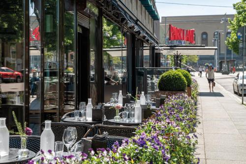 an outdoor restaurant with tables and flowers on a sidewalk at Elite Park Avenue Hotel in Gothenburg