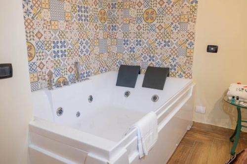 a white tub in a bathroom with a tile wall at Hotel Sirio in Boscotrecase