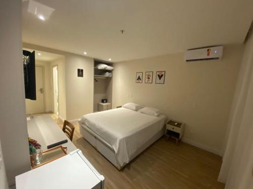 a bedroom with a white bed and a desk at Flat Apart Hotel América Campos dos Goytacazes in Campos dos Goytacazes