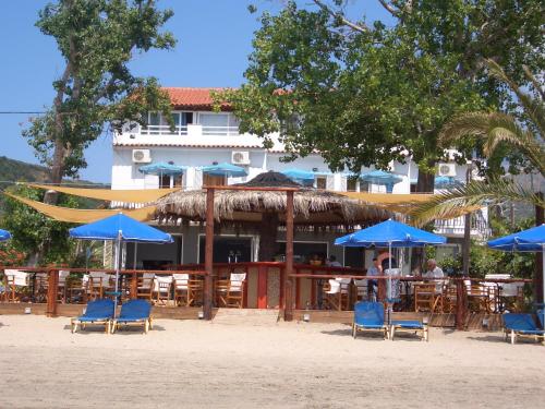 a restaurant with blue chairs and umbrellas on the beach at Hercules Sea Front Studios in Katelios