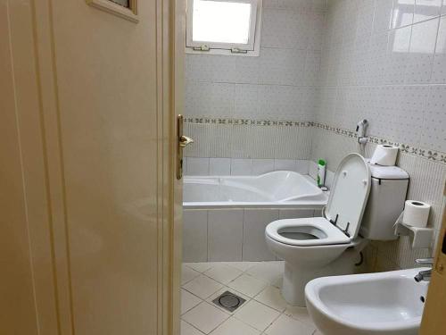 y baño con aseo y bañera. en Furnished room in a villa in town center. With private bathroom, en El Ain