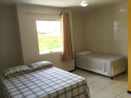 two beds in a room with a window at Pousada Casa Bella in Campina Grande