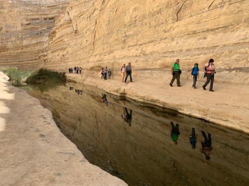 a group of people walking along the side of a river at Khan Alsira - חאן אלסרה in Alsira