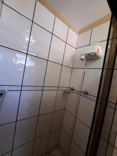 a shower stall with a white tiled wall at Casa da mãe in Aparecida
