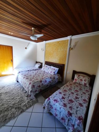 a bedroom with two beds and a ceiling at Casa da mãe in Aparecida