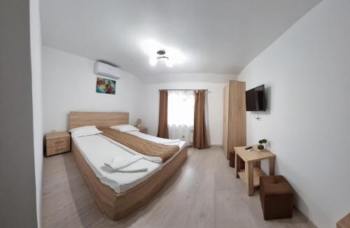 sypialnia z dużym łóżkiem i telewizorem w obiekcie Cusali Pensiune w mieście Topolovăţu Mare